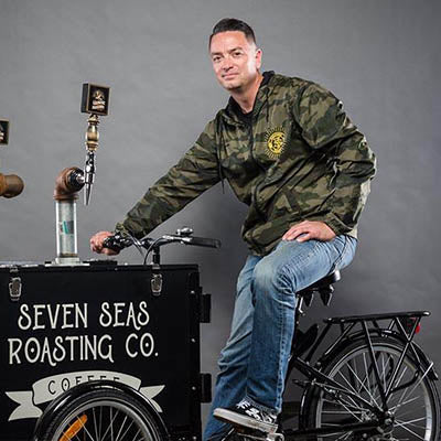 eric dobbs, caucasian male on cold brew bike wearing camo jacket and blue jeans