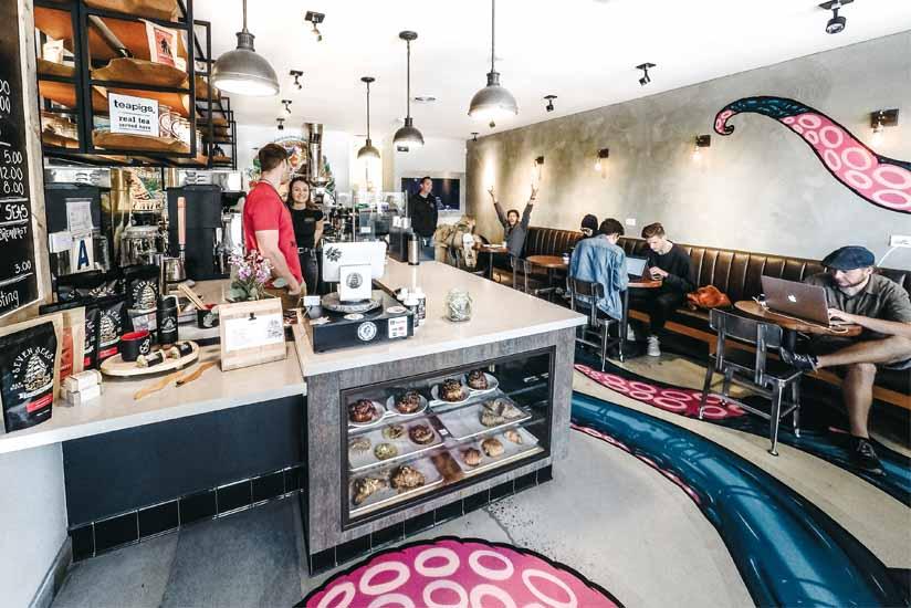 Inside of seven seas roasting south park location with two baristas and a couple customers enjoying coffee.